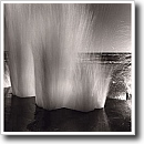 Black and white photograph of a wave splashing over a pier